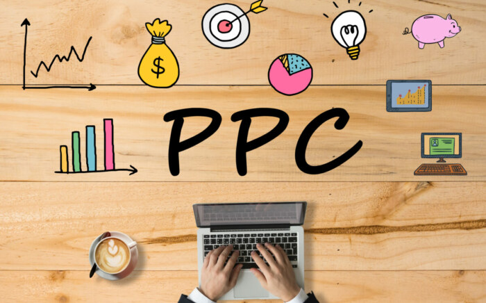 A wooden table with digital marketing icons and a businessman searching on a laptop, representing the concept of pay-per-click (PPC) in digital marketing.