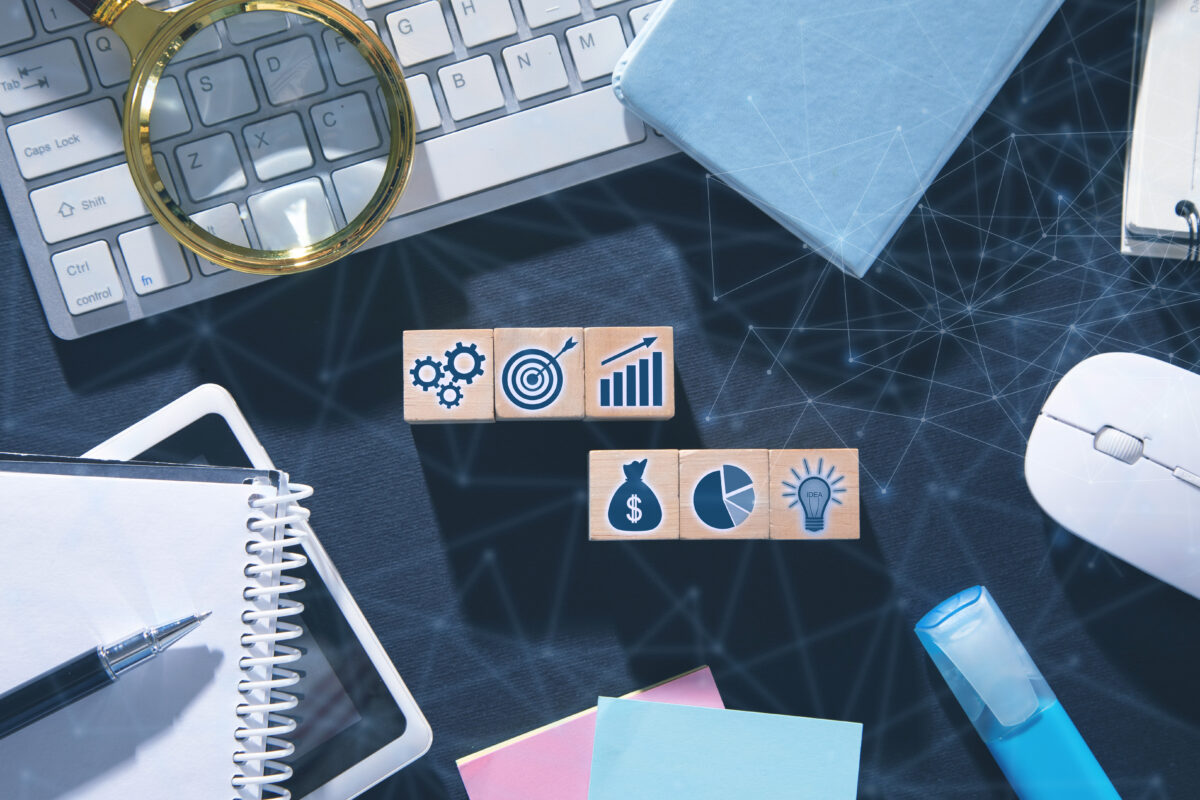 Wooden cubes with business symbols representing goal achievement in a business process.